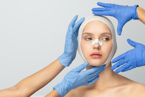 A woman's face framed by gloved hands after cosmetic surgery