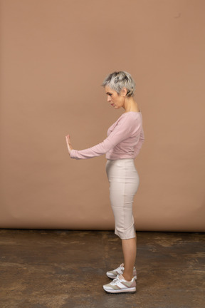 Side view of a woman in casual clothes showing stop gesture
