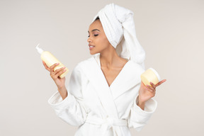 Black woman in white bathrobe and head towel enjoying her skin care routine