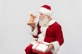 Babbo natale sorpreso guardando giocattolo di peluche di cervo