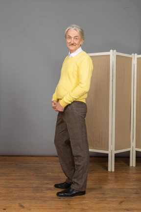 Three-quarter view of a smiling shy old man putting hands together