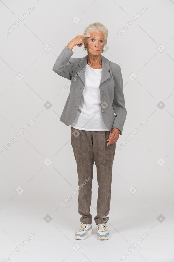 손가락으로 이마를 만지는 양복을 입은 노부인의 전면 모습