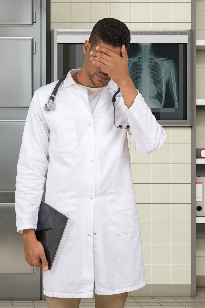 A doctor covering his eyes
