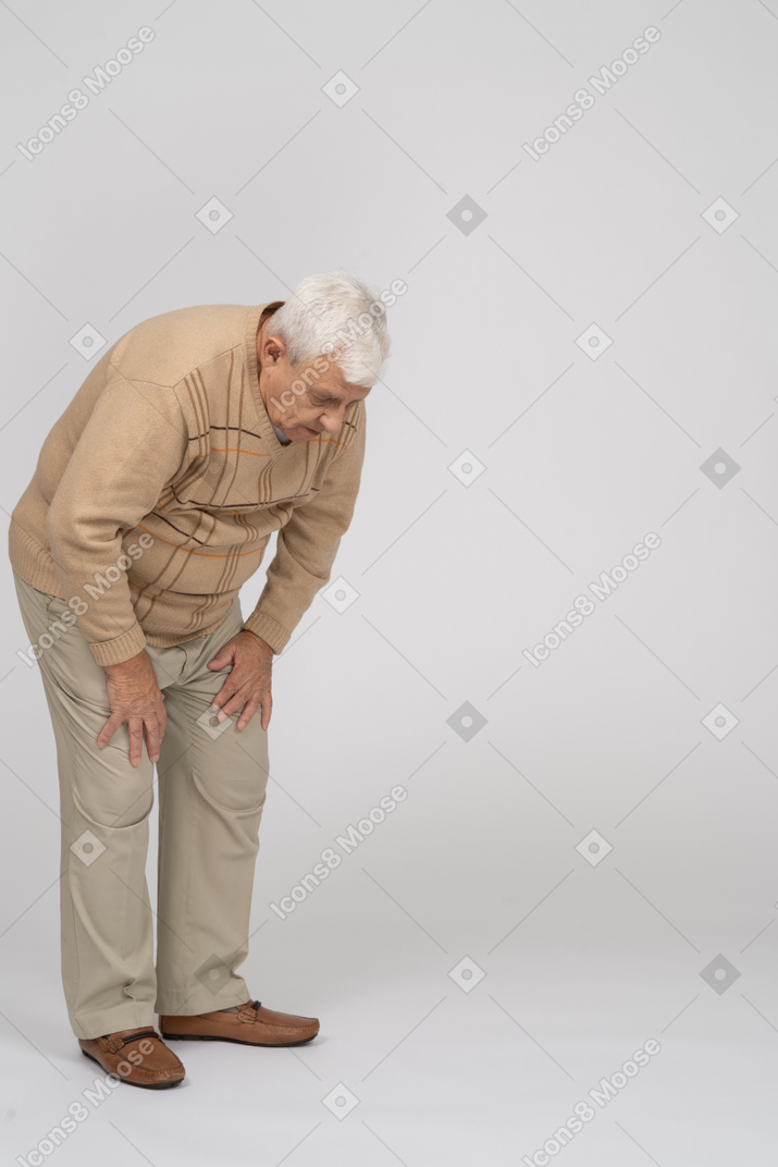 Old man in casual clothes bending down