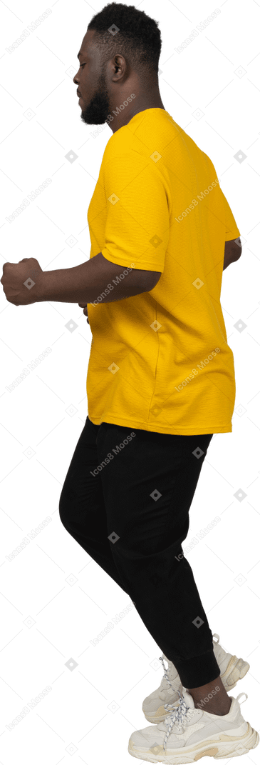 黄色のtシャツを着て走っている若い浅黒い肌の男の側面図