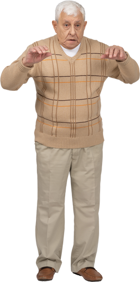 Front view of an old man in casual clothes scaring someone