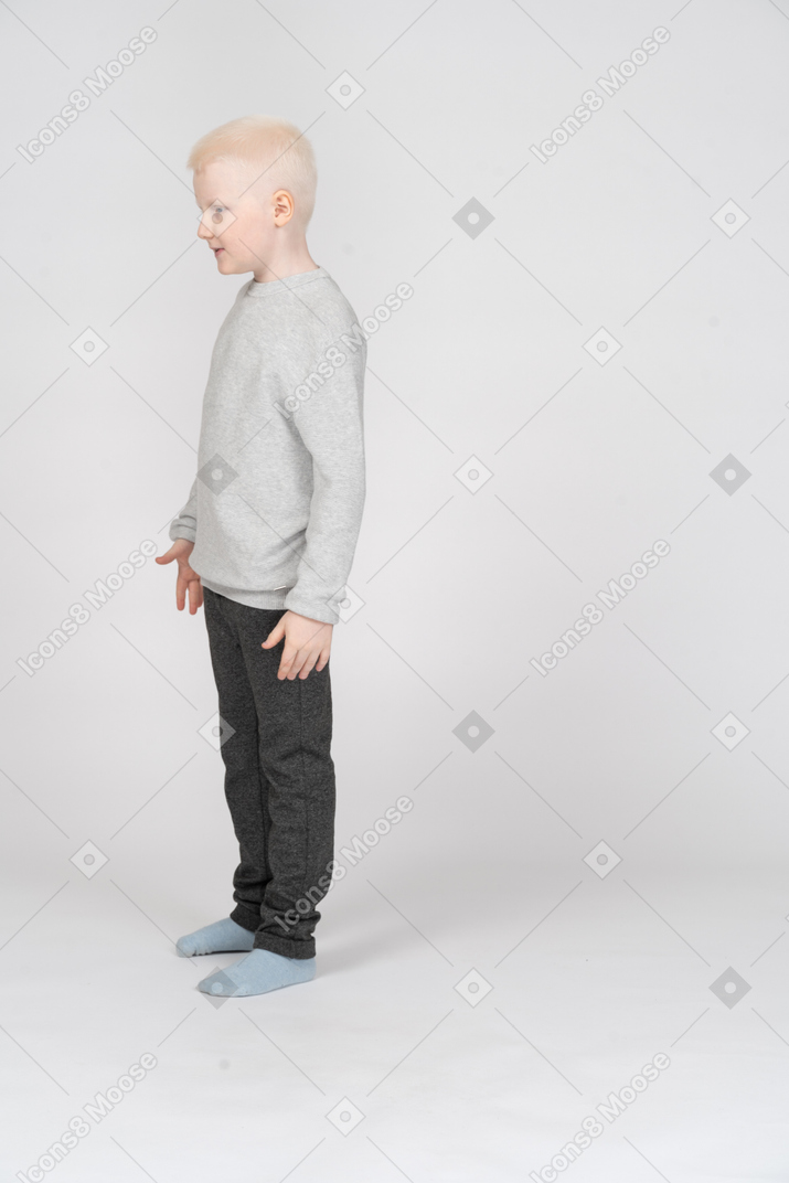 Three quarter view of a little boy standing and saying something