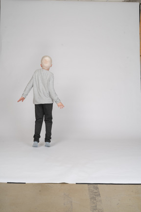 Vista posteriore di un ragazzo in abiti casual in piedi sulla punta dei piedi