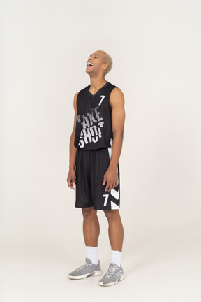 Vista de tres cuartos de un joven jugador de baloncesto masculino riendo levantando la cabeza