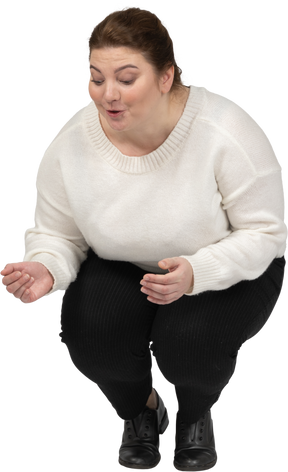 Vista frontale di una donna grassoccia felice in abiti casual accovacciata