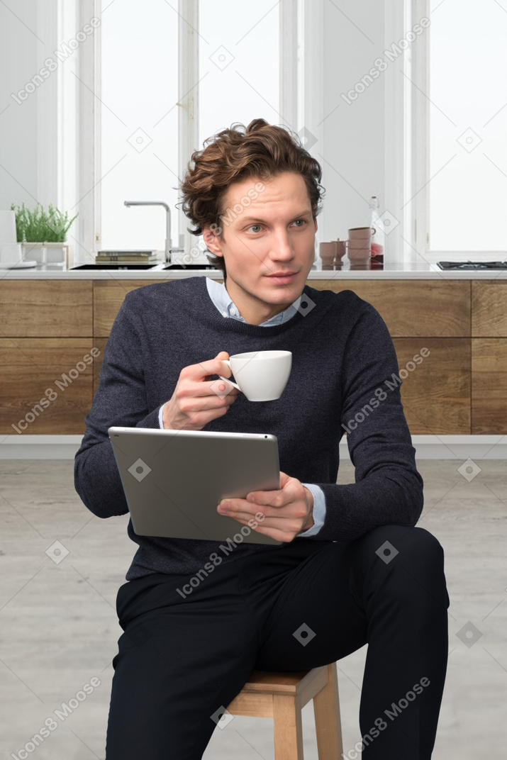 A man sitting on a stool holding a cup of coffee