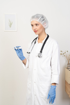 Three-quarter view of a young female doctor with stethoscope holding thermometer