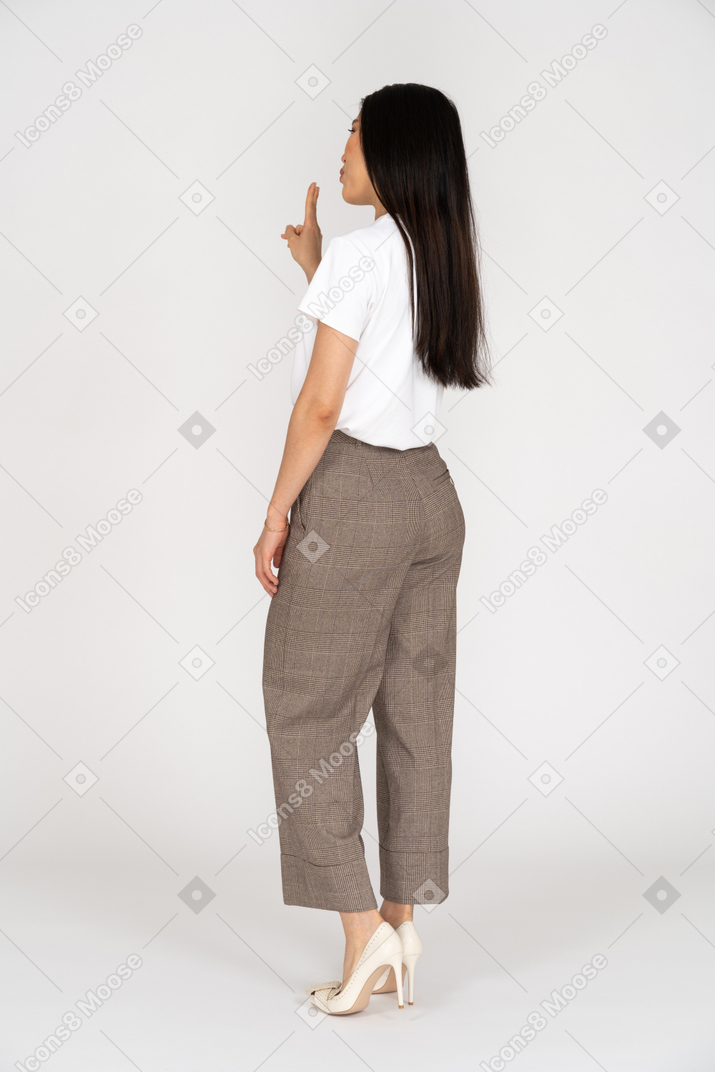 Three-quarter back view of a young woman in breeches showing peace sign