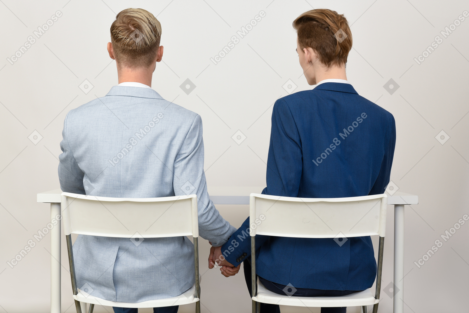Dos colegas masculinos tomados de las manos debajo de la mesa.