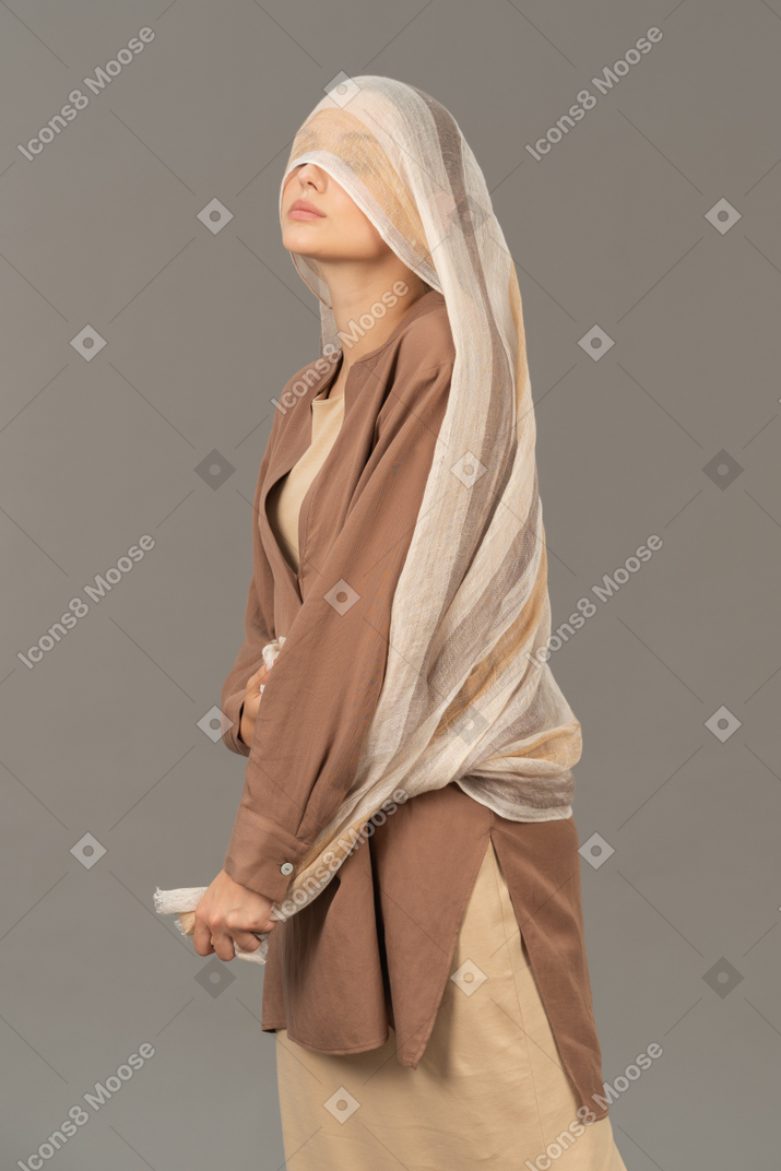 Mujer joven que cubre sus ojos con una bufanda