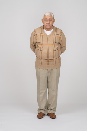 Vista frontal de um velho em roupas casuais em pé com as mãos atrás das costas