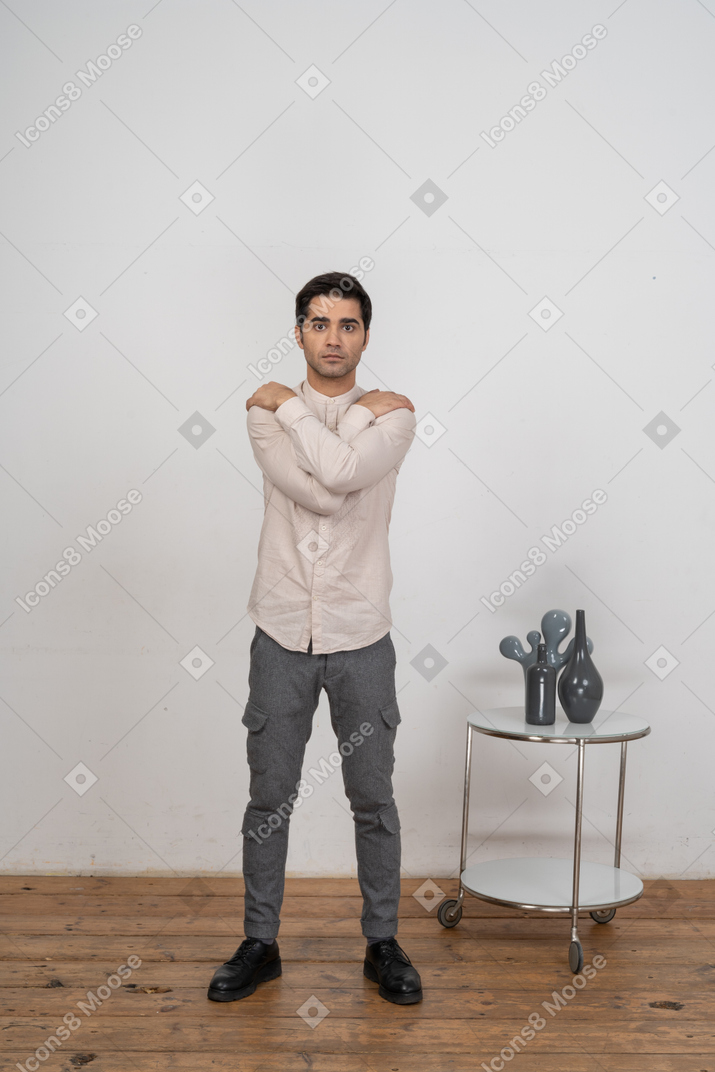Front view of a man in casual clothes hugging himself