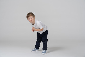 Cheerful little boy bending forward