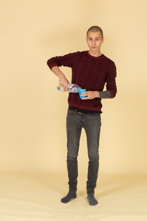 Front view of a young man in red pullover pouring some water