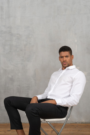 Young man sitting on a chair and looking at camera