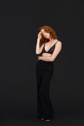 A frontal view of the cute red haired girl posing on the black background with the eyes closed