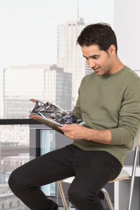 年轻人坐在椅子上，读一本杂志