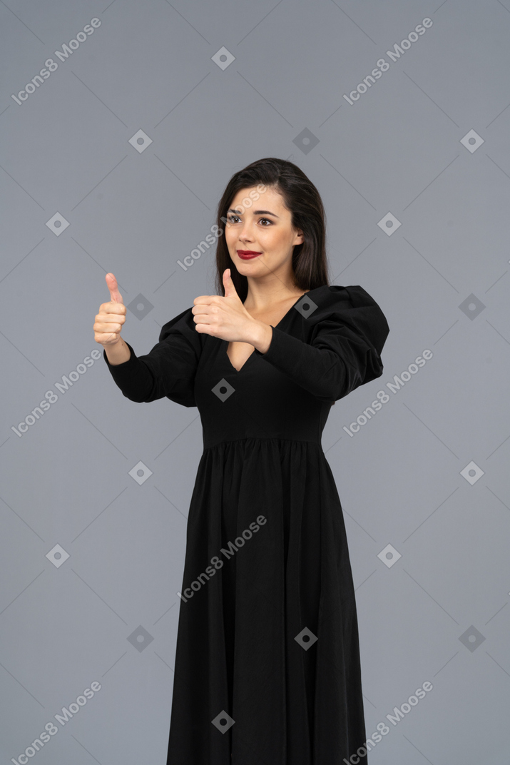Three-quarter view of a smiling young lady in a black dress showing thumbs up