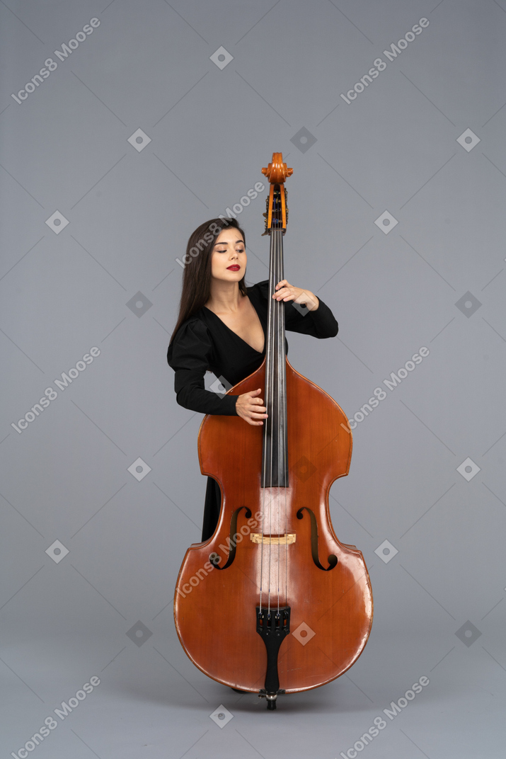 Vista frontale di una giovane donna in abito nero che suona il suo contrabbasso