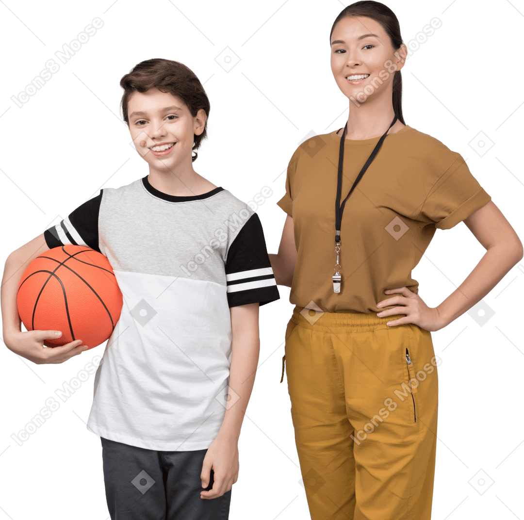 Учитель физкультуры стоит рядом с учеником, который держит баскетбольный мяч
