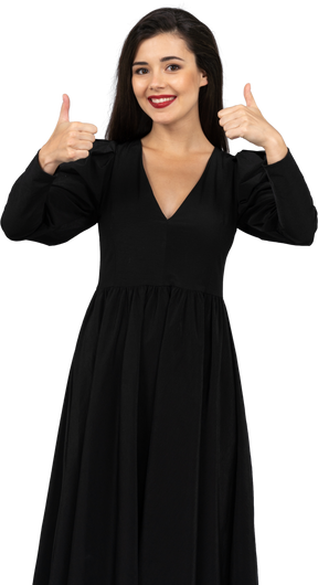 Vista frontal de uma jovem em um vestido preto mostrando os polegares para cima