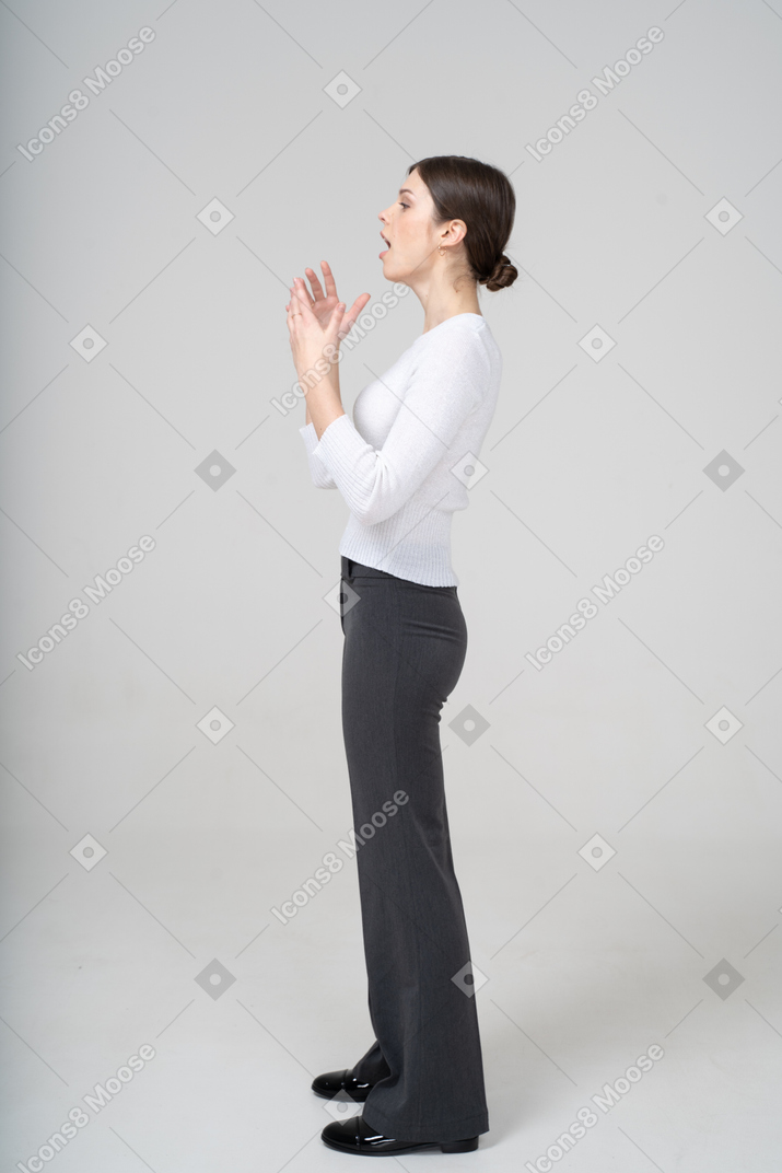 Side view of a woman in black pants and white shirt gesturing
