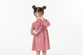 Маленькая девочка держит розовый пластиковый стаканчик