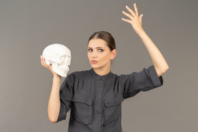 Front view of a young woman in a jumpsuit holding a plaster skull