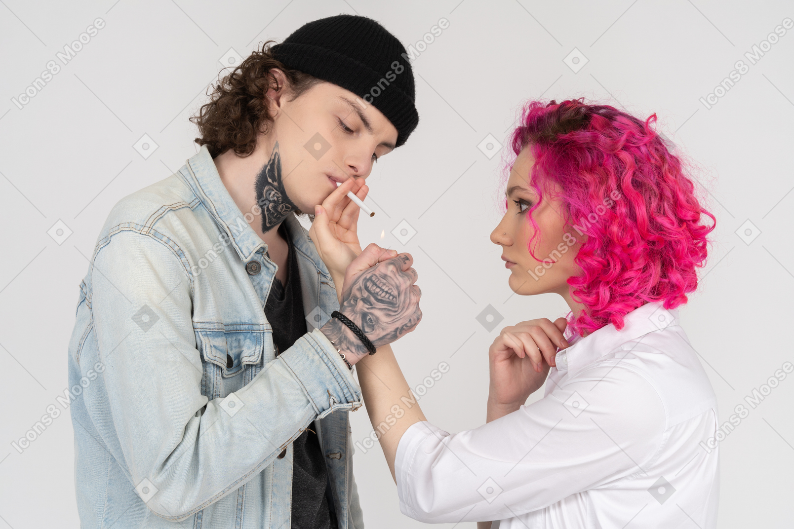 Young tattooed man in a denim shirt giving a smoke to his pink-haired girlfriend