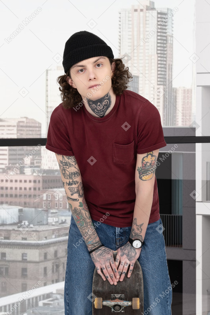 Молодой татуированный парень стоит на балконе