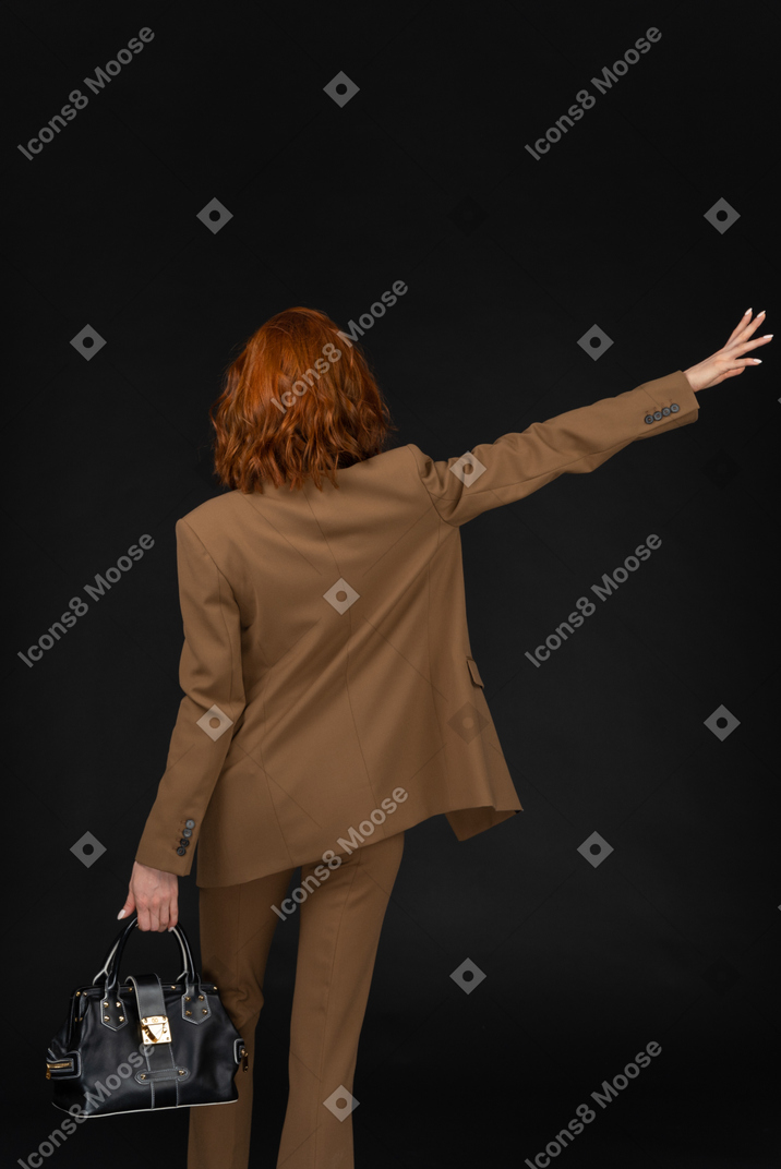 Back view of a businesswoman hailing a cab