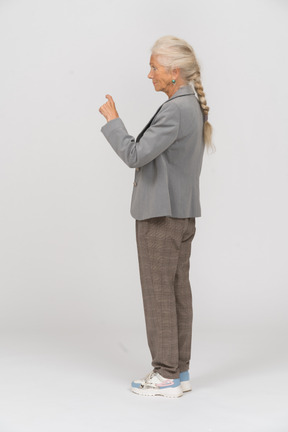 Vista lateral de uma senhora idosa de terno apontando com um dedo