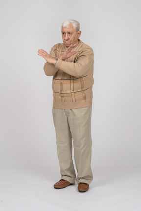 Вид спереди грустного старика в повседневной одежде, показывающего стоп-жест