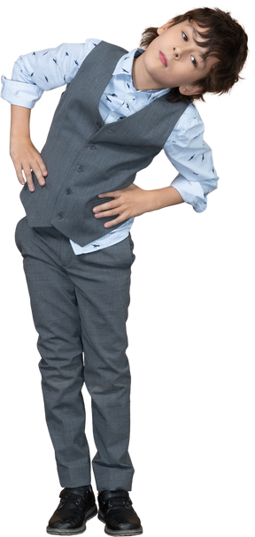 Vue de face d'un garçon en costume posant avec les mains sur les hanches et regardant la caméra