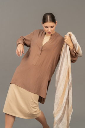 Mujer joven en ropa beige posando con bufanda