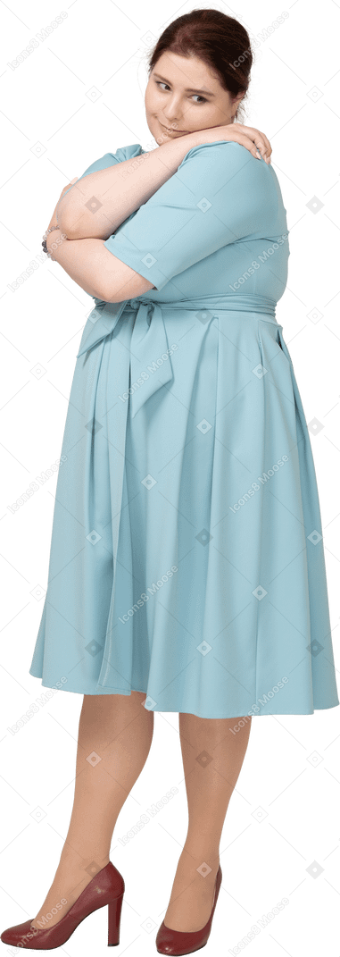Вид спереди женщины в синем платье, обнимающей себя