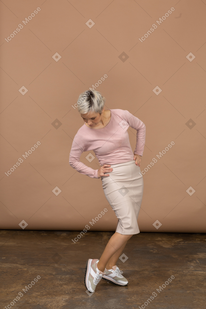 一个穿着休闲服的女人双手叉腰站着，看着她的运动鞋的前视图
