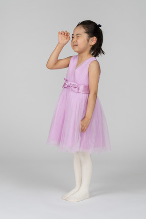 Petite fille en robe rose essayant de voir quelque chose de minuscule