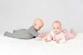 Babies twins lying on the stomach and holding stuffed toy