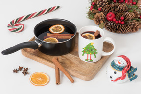 Cup and pan with mulled wine and christmas decorations near it