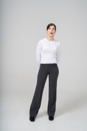 Vista frontal de uma mulher impressionada em blusa branca e calça preta