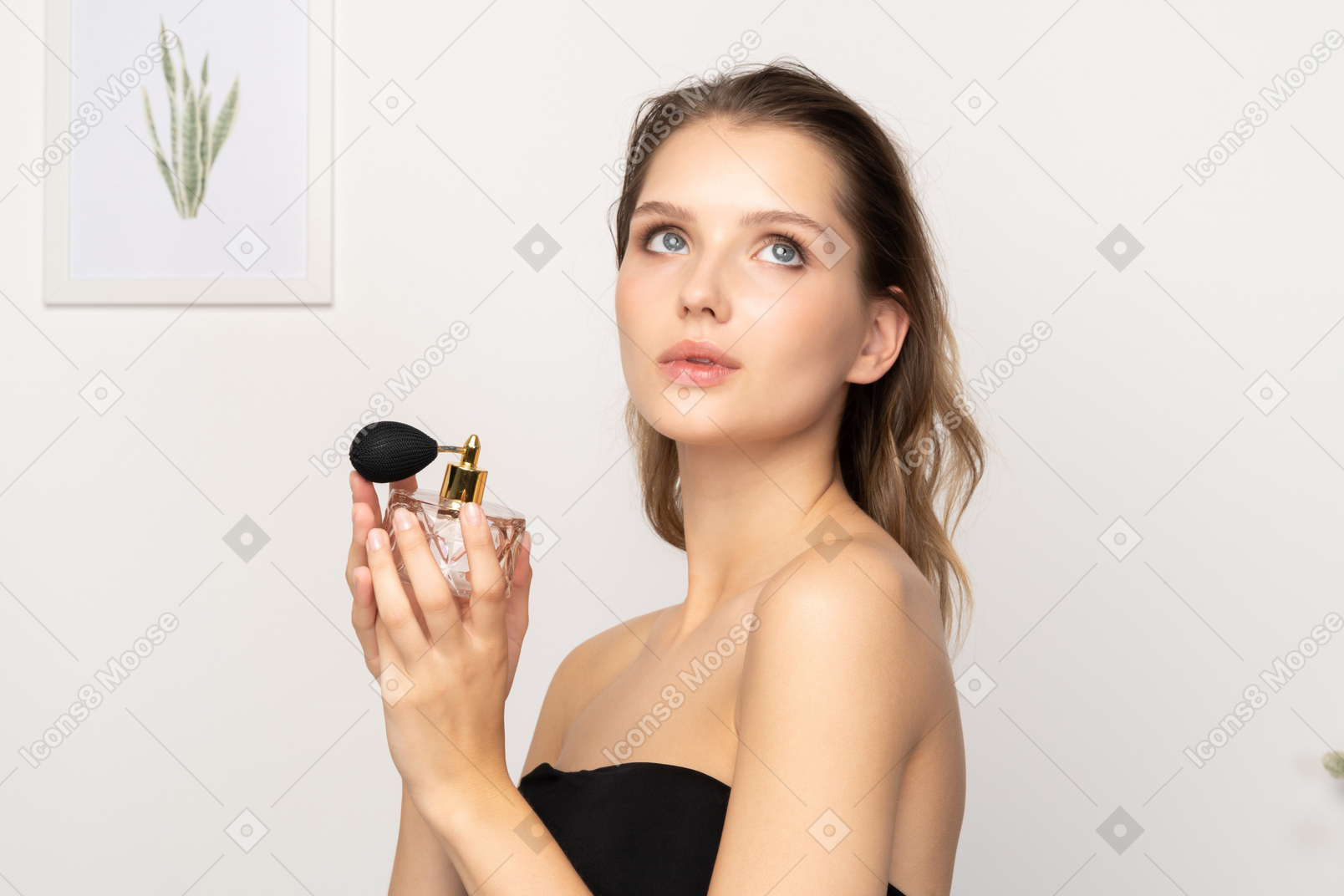 Three-quarter view of a sensual young woman holding a bottle of perfume