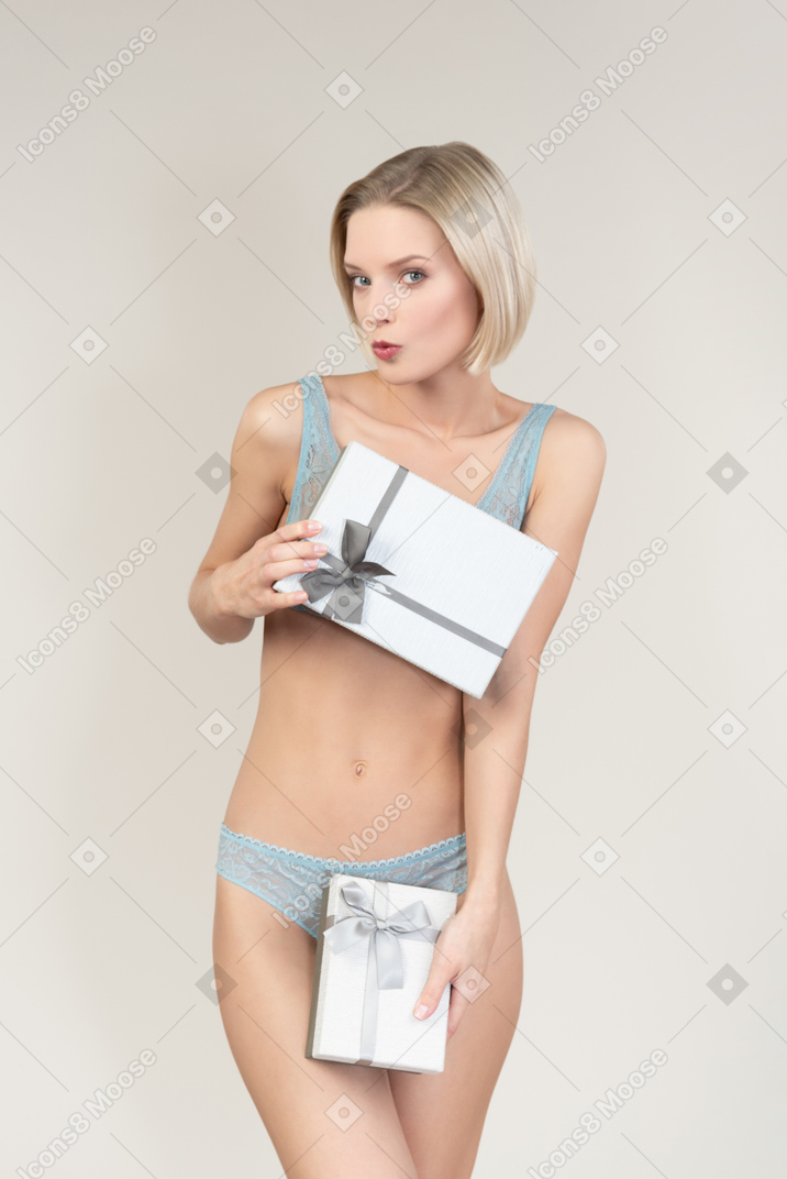 Sexy junge frau in der wäsche, die geschenkbox hält