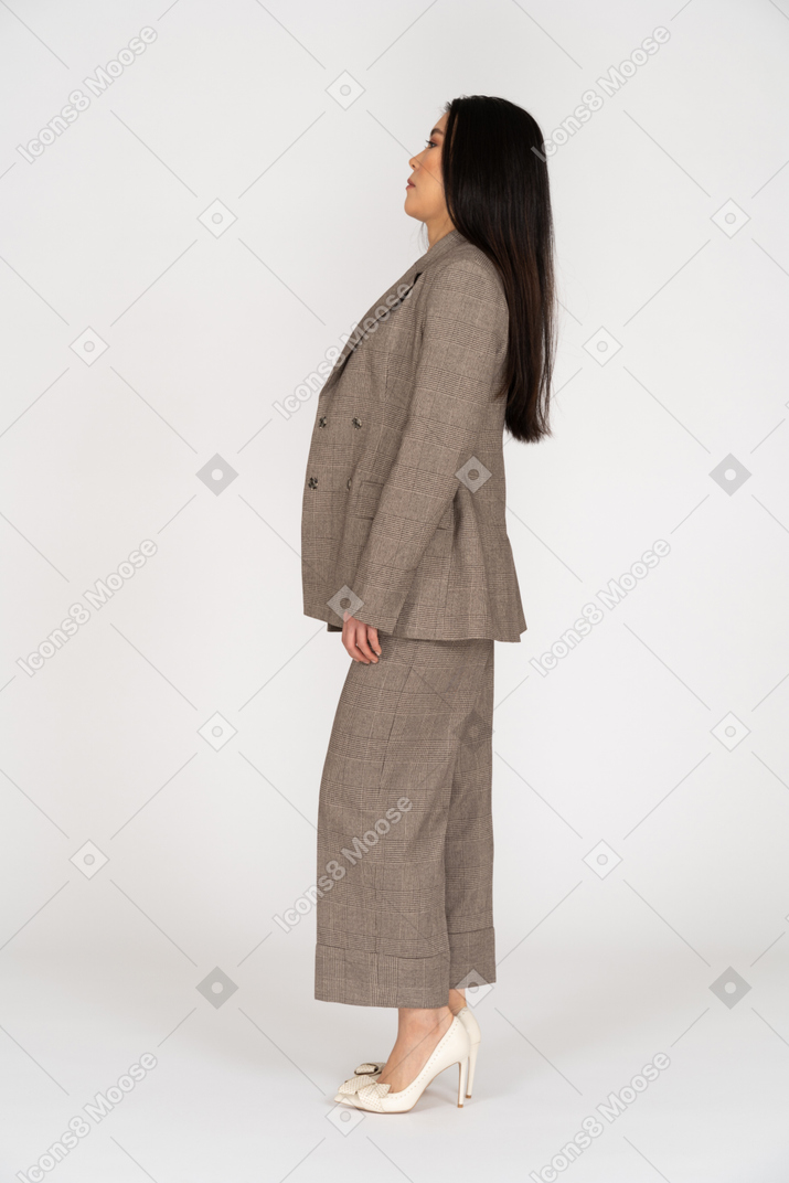 Vista lateral de uma jovem confusa em um terno marrom, recostada