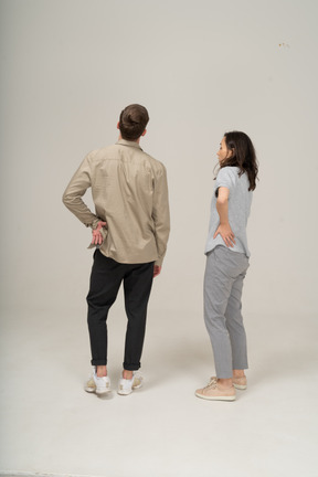 Jeune homme et femme debout sur les hanches et regardant au loin